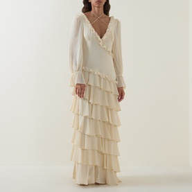 Model wearing Anne Louise Boutique Cream Dress with tiered ruffle skirt, sheer long sleeves, and V-neckline with ruffle trim
