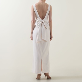 Model wearing Anne Louise Boutique Rose Bow Dress in Rose, showing low V-back with oversized bow detail and maxi length with back slit