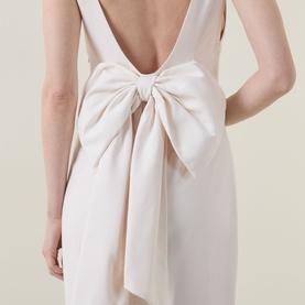 Model wearing Anne Louise Boutique Rose Bow Dress in rose, showing low V-back with oversized bow detail at waist