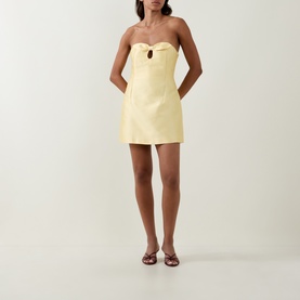 Model wearing Bernadette Soft Yellow strapless mini dress with keyhole bust detail, styled with burgundy strappy heeled sandals