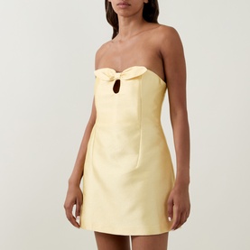 Model wearing Bernadette soft yellow strapless mini dress with bow detail and keyhole cutout at bust