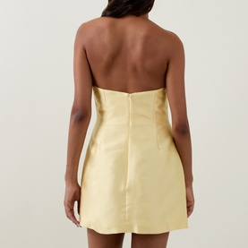 Model wearing Bernadette soft yellow strapless mini dress, back view showing structured bodice and concealed zip fastening.