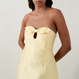 Model wearing Bernadette soft yellow strapless mini dress with bow detail and keyhole cutout at bust
