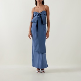 Model wearing Bernadette mid blue satin maxi dress with oversized bow detail and thin straps, styled with white heeled mules