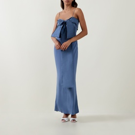 Model wearing Bernadette mid blue maxi dress with oversized front bow detail and thin straps, styled with white heeled mules