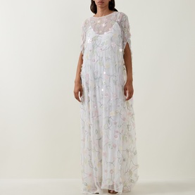 Model wearing Bernadette Clematis Emb White maxi dress with floral embellishments, sheer cape overlay, and floor-length silhouette.