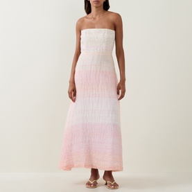 Model wearing Bernadette Dress in Spanish Seaside, strapless maxi silhouette with ombr&eacute; pink gradient, styled with strappy flat sandals