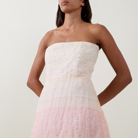 Model wearing Bernadette strapless dress in Spanish Seaside, ombre pink-to-white textured silk-linen blend, midi length visible.