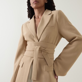 Model wearing Odd Muse camel belted blazer top with notch lapel and wide sleeves, styled with light trousers.