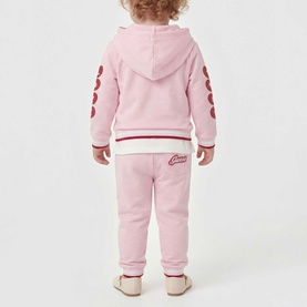 Model wearing Guess Polly Pink 2-piece set with heart-sleeve hoodie and joggers, viewed from behind