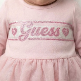 Close-up of Guess pink baby dress with glitter logo and heart motifs on waistband, soft tulle skirt detail visible
