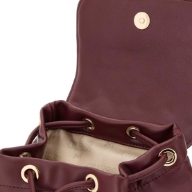 Guess deep maroon mini bag, open top view showing gold-tone eyelets, drawstring detail and gold snap closure, cream interior lining visible