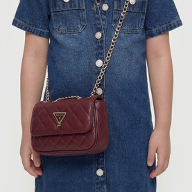 Model carrying Guess deep maroon quilted mini crossbody bag with gold chain strap and triangle logo, styled with denim dress
