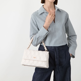 Model carrying cream quilted shoulder bag with gold chain strap, styled with striped shirt and navy wide-leg trousers