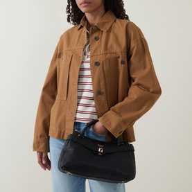 Model carrying Guess Ella Logo Satchel Bag in black logo, gold-tone hardware, styled with tan jacket and striped tee