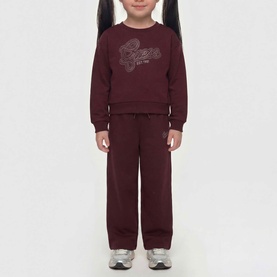 Model wearing Guess deep maroon sweat top with rhinestone logo, styled with matching wide-leg joggers and silver trainers