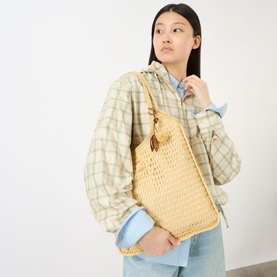Model carrying Miu Miu Ivy Crochet Net Tote Bag in Natural, with gold-tone hardware, worn crossbody over a checked jacket.
