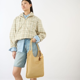 Model carrying Miu Miu Ivy Crochet Net Tote Bag in natural, gold-tone hardware, styled with check jacket and denim shorts