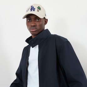 Model with New Era LA Dodgers MLB City Icon 9FORTY Cap in cream, featuring embroidered LA logo and palm trees, curved visor, styled with navy jacket.