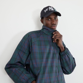 Model with New Era New York Yankees MLB City Icon 9FORTY Cap in navy, styled with a green tartan high-neck pullover.