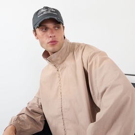 Model with New Era Wash Distress 9TWENTY A-Frame Cap in charcoal, featuring distressed curved visor and heritage script embroidery, styled with beige