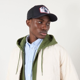 Model with New Era LA Dodgers MLB Patch 9FORTY Trucker Cap in navy, styled with cream jacket and olive hoodie