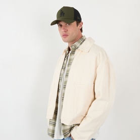 Model with New Era LA Dodgers MLB Sport 9FORTY Trucker Cap in green, styled with cream harrington jacket and plaid shirt.