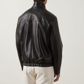 Model wearing Canali black leather casual jacket, rear view, with ribbed hem and collar, styled with cream trousers