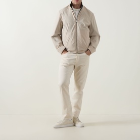 Model wearing Canali black casual jacket with cream trousers and white trainers, hands in pockets