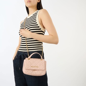 Model carrying Mario Valentino Ocarina Flap Chain Crossbody Bag in pink with gold-tone chain strap and quilted diamond stitching, styled with striped