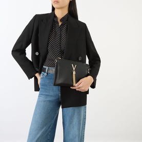 Model carrying Mario Valentino Divina Logo Clutch Bag in black with gold-tone V-logo hardware and tassel charm, styled with black blazer and jeans.