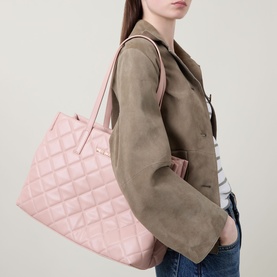 Model carrying Mario Valentino Ocarina Logo Shopper Bag in pink quilted finish with gold-toned hardware and carry handles, styled with khaki jacket