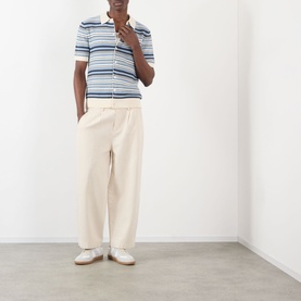 Model wearing NN07 Nolan Striped Polo Cardigan in Navy Multi with cream wide-leg trousers and white trainers.