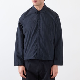 Model wearing NN07 Fenton Water Repellent Jacket in Deep Navy, with shirt collar, front button closure, and lightweight textured finish, styled with