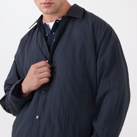 Model wearing NN07 Fenton Water Repellent Jacket in Deep Navy, showing shirt collar and front button closure, styled with a blue shirt and white tee.