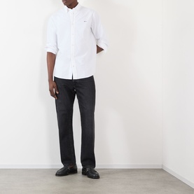 Model wearing NN07 Colby Logo Shirt in white with button-down collar, styled with dark jeans and black loafers.