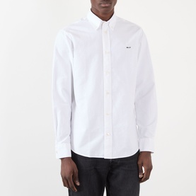 Model wearing NN07 Colby Logo Shirt in white, featuring button-down collar, long sleeves, and small chest logo, styled with dark jeans.