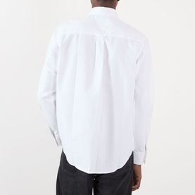Model wearing NN07 Colby Logo Shirt in white, rear view, showing back yoke detail, long sleeves with buttoned cuffs, paired with dark trousers.