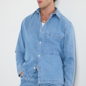 Model wearing NN07 blue denim casual shirt with chest pocket, relaxed fit, button-down front, paired with a gold chain necklace