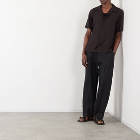 Model wearing NN07 Dusky Port casual shirt with black wide-leg trousers and brown sandals, full-length view.