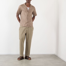 Model wearing NN07 Julio Linen Shirt in Clay Mirage with camp collar and short sleeves, styled with khaki trousers and brown sandals.