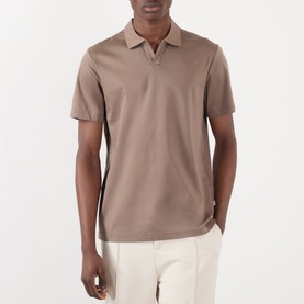 Model wearing taupe short-sleeve polo shirt with open collar, styled with cream trousers