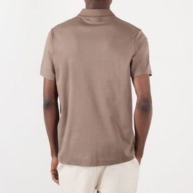 Model wearing taupe short-sleeve polo shirt, back view, styled with cream trousers