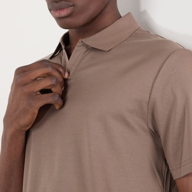 Model wearing a taupe short-sleeve polo shirt, close-up view of collar and chest detail