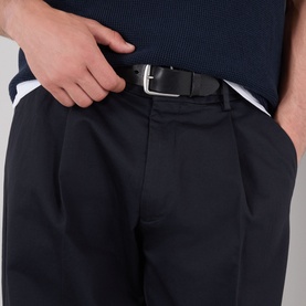 Model wearing NN07 Kay Relaxed Fit Pleated Trousers in navy blue, with double front pleats and black leather belt with silver buckle.