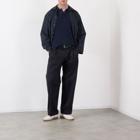 Model wearing NN07 Kay Relaxed Fit Pleated Trousers in navy blue with a navy hoodie, dark jacket and white shoes.