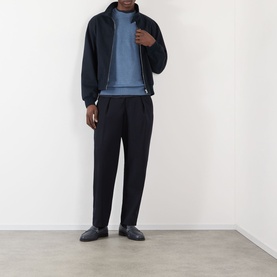 Model wearing NN07 Stone Blue linen crew neck, styled with navy zip-up jacket and tapered black trousers