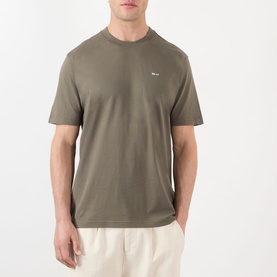Model wearing NN07 T-Shirt in Capers green, crew neck, short sleeves, small logo detail, styled with cream trousers