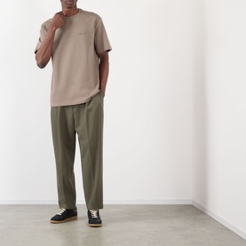 Model wearing NN07 Clay Mirage T-shirt with olive wide-leg trousers and black low-top trainers.