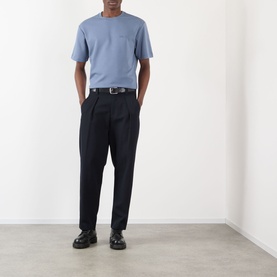 Model wearing blue crew neck T-shirt and black tapered trousers with belt, styled with black chunky sole loafers
